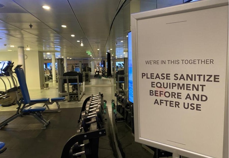 健身房内的警示牌，提醒旅客使用设备前后都要消毒