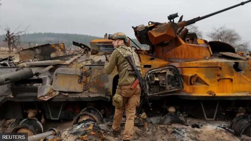 A Ukrainian soldier inspects a destroyed Russian APC near Kyiv