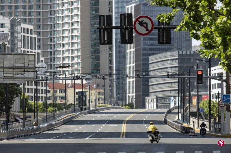 上海封城期间，快递员骑着电单车在几乎空无一人的大街上行驶