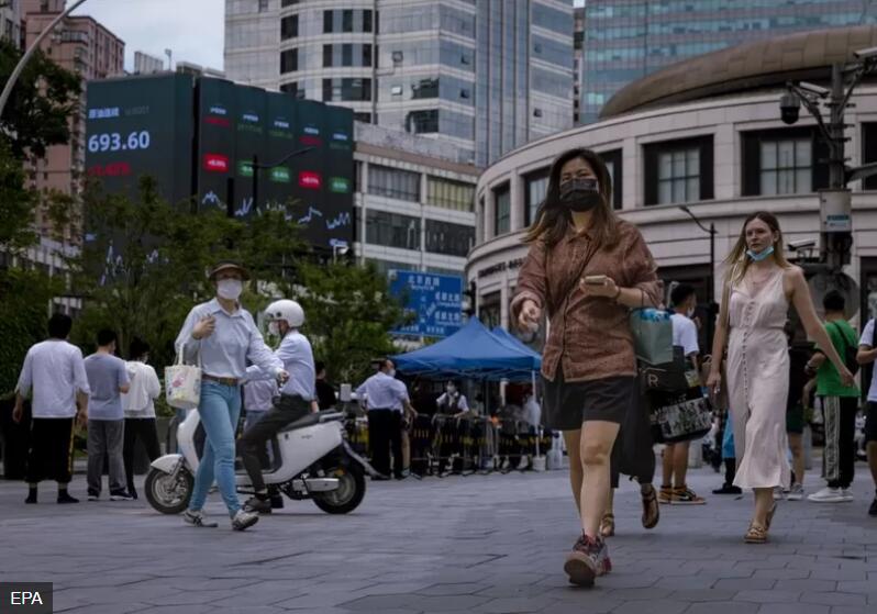 行人走在显示最新经济和证券交易所子信息的大屏幕