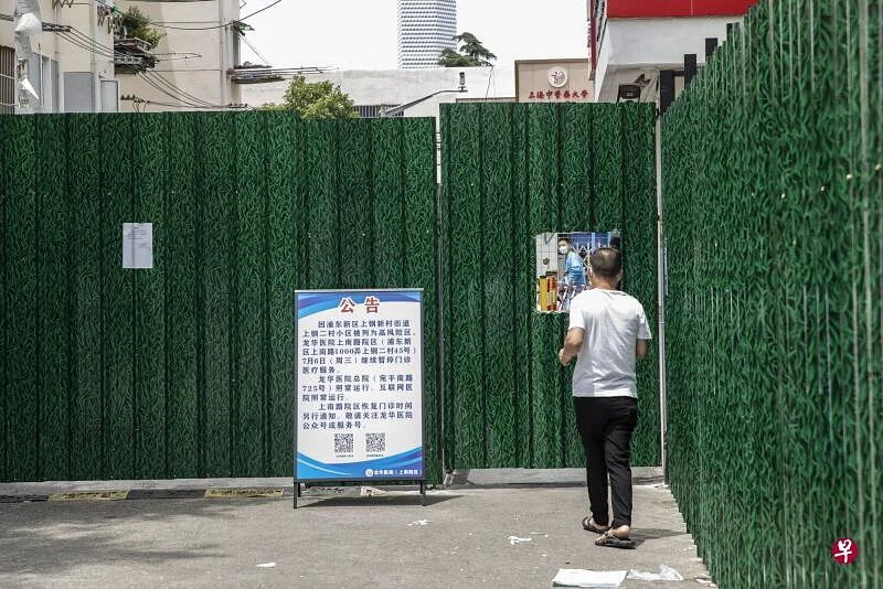 一名行人周三（7月6日）站在上海一处被围封的小区外