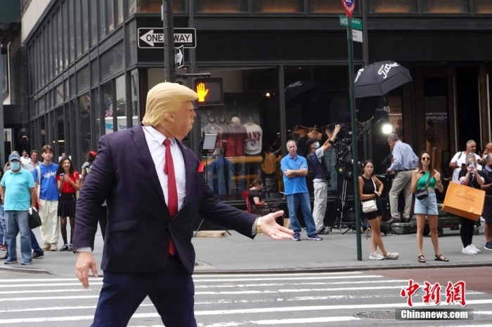 一名戴着面具的示威者在美国纽约特朗普大厦外模仿美国前总统特朗普