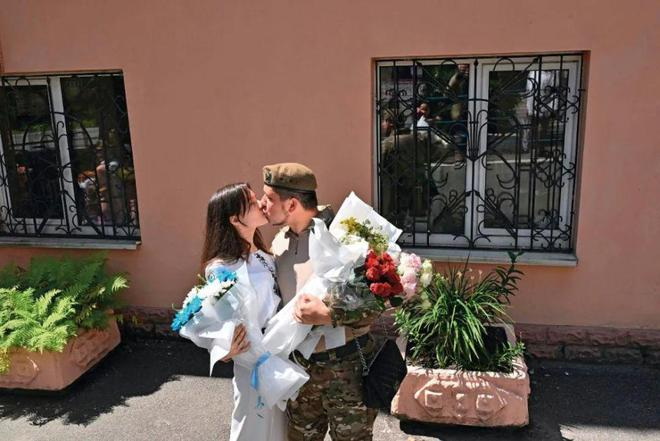乌克兰基辅，婚礼结束后，25岁的乌克兰军人Vitaliy在登记处办公室外亲吻妻子 ... ...