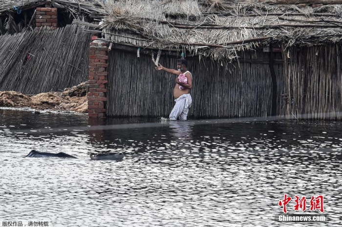 巴基斯坦信德省，民众在大雨后涉水穿过洪水泛滥的地区
