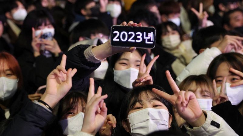 在韩国首尔，戴着口罩的民众聚集在一起迎接新年